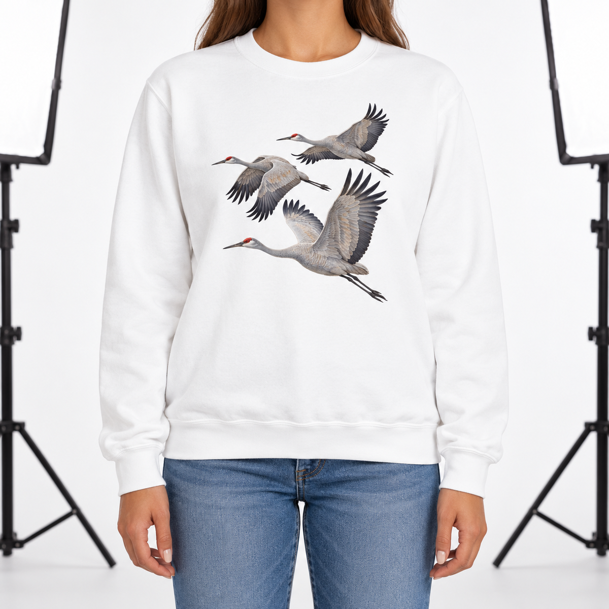 Woman wearing a White Comfort Colors 1566 crewneck sweatshirt with three sandhill cranes in flight printed on the chest, no text