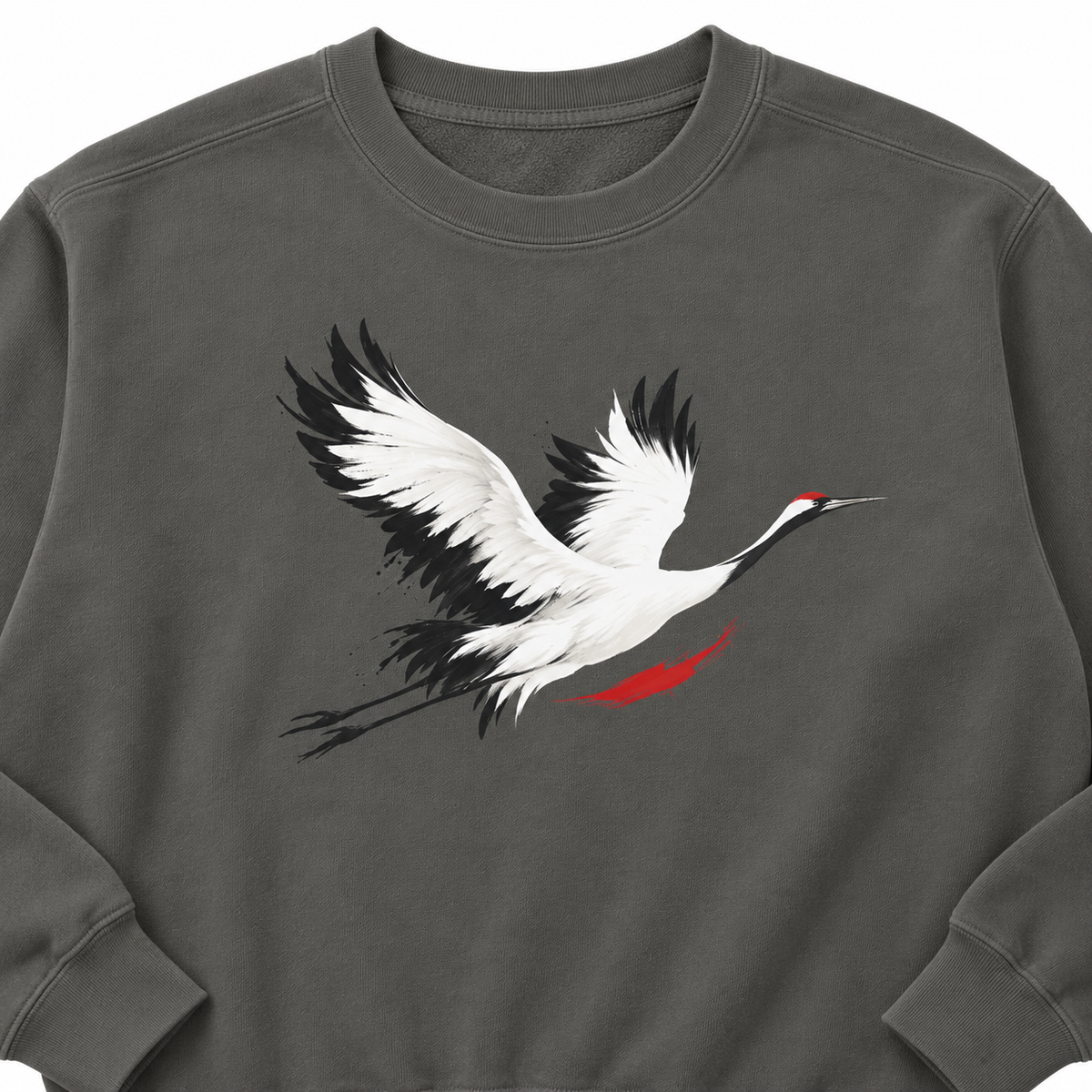 Close-up of the minimalist red-crowned crane in flight print — white wings edged in black, vermilion crown — on a Pepper Comfort Colors 1566 crewneck sweatshirt