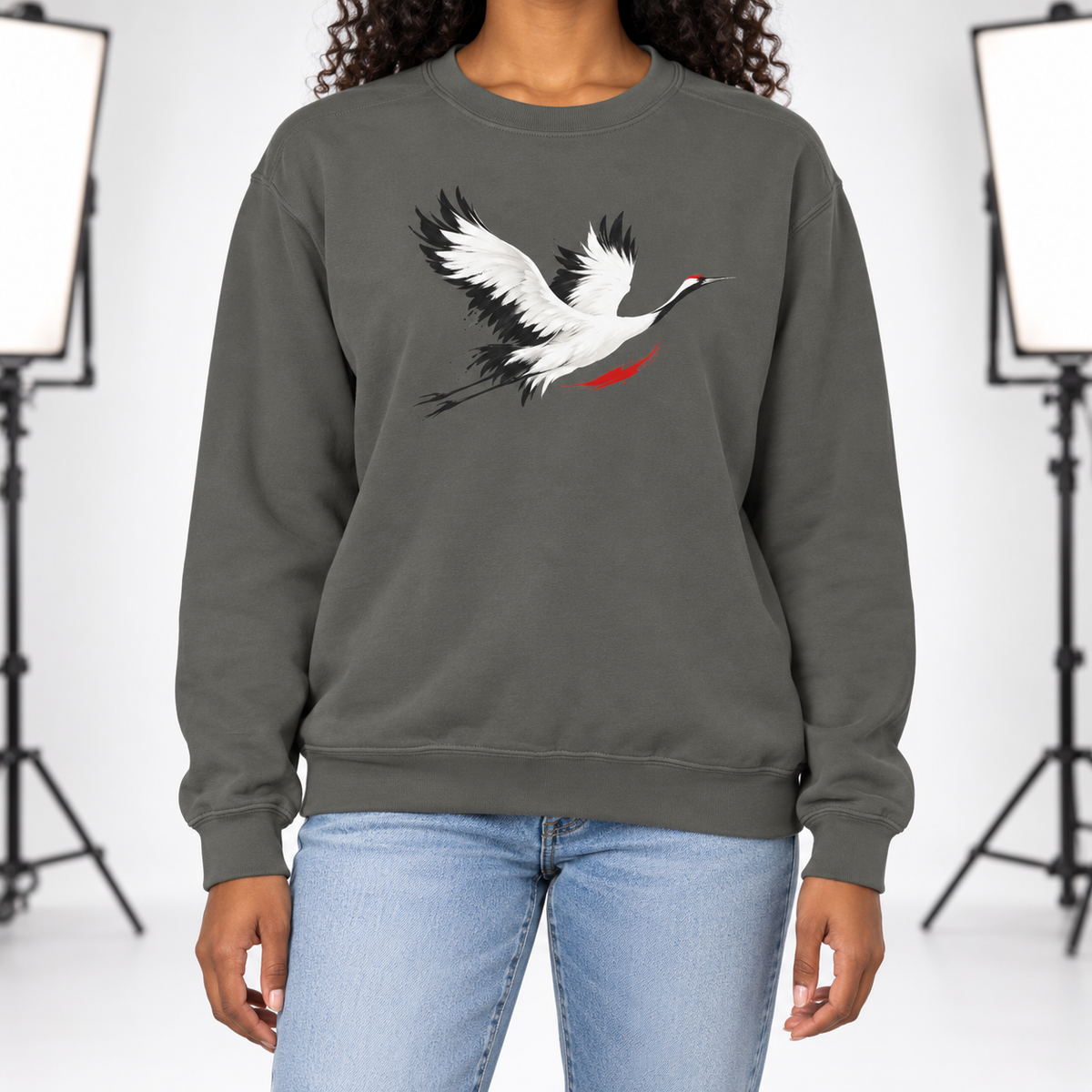 Pepper Comfort Colors 1566 crewneck sweatshirt with a minimalist red-crowned crane in flight printed on the chest, worn by a model