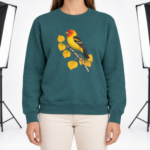 Woman wearing the Western Tanager on Golden Aspen sweatshirt in Blue Spruce, a yellow tanager with a red head on a branch of golden aspen leaves, large centered chest print